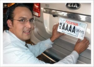 Diego Espinoza, founder of the UAMS License Plate Program, putting the special UAMS license plate on a car