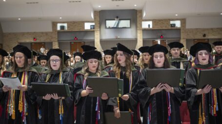 UAMS students wear their graduation regalia and follow along with their programs during UAMS commencement.